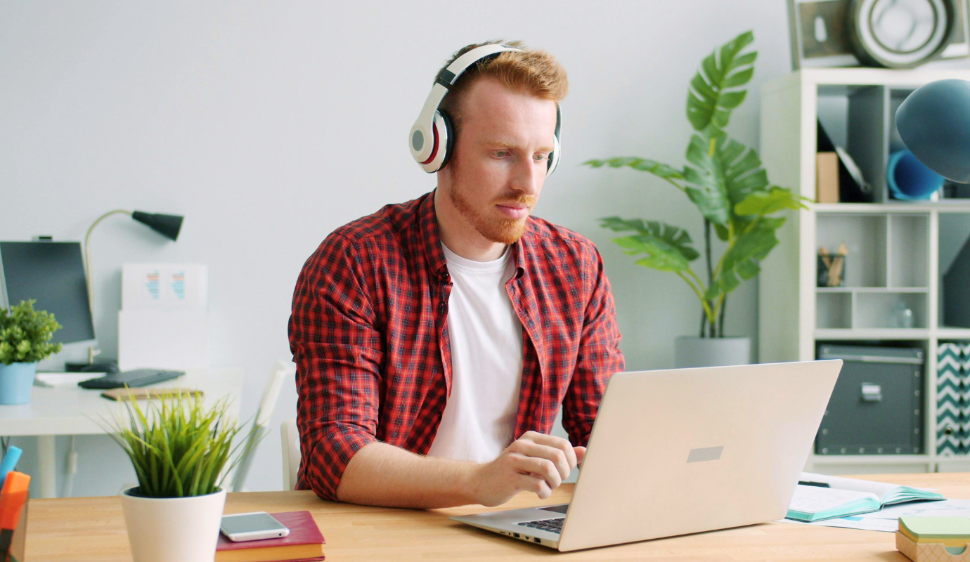 Man at home doing his hybrid work on laptop with headphones.